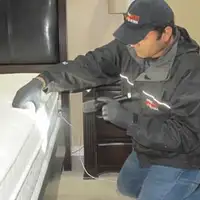 Bed bug inspection technician checking a mattress and bed frame for signs of infestation in Tallahassee, FL