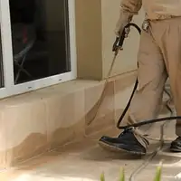 General pest control technician spraying exterior perimeter around a home in Tallahassee, FL