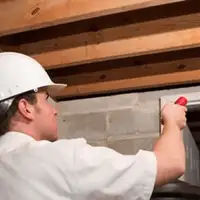 Termite inspection technician checking a basement wall and framing for termite activity in Tallahassee, FL